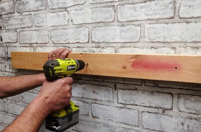 Person drilling timber into wall.