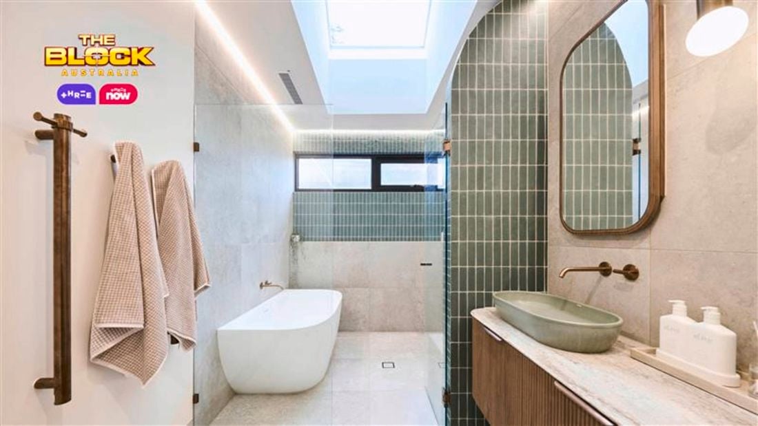 Green and white coloured bathroom with a timber fluted profile vanity and marble benchtop and bath.