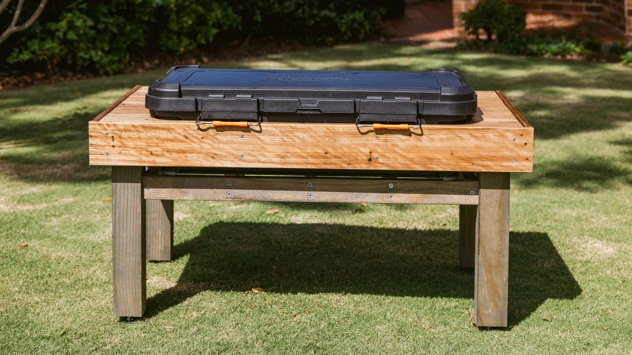 A raised wooden dog-wash station standing alone on lawn, with a closed black wash tub mounted on top.