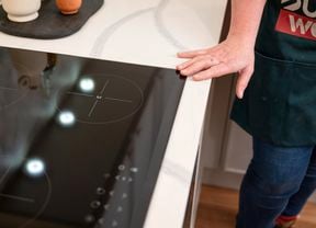A person keeping his hand on an electric cooktop.