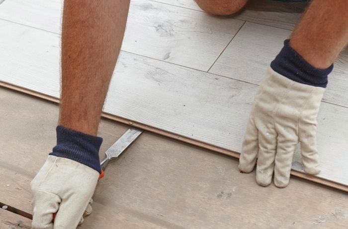 Person removing laminate flooring.