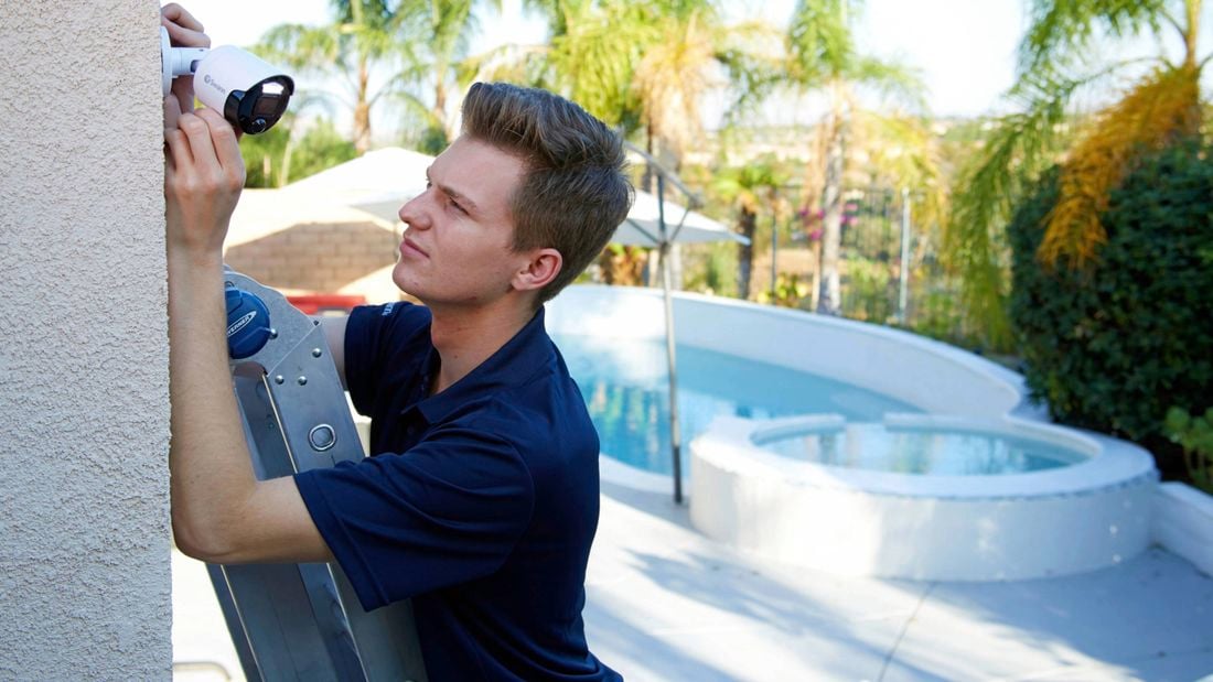 An image of a Swann security camera being installed by a tradesman on a ladder