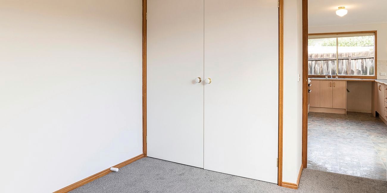 Room with cream walls, grey carpet and cupboard.