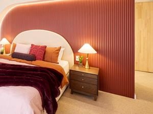 Bedroom with red feature wall, arch lighting, and layered bedding in warm tones.