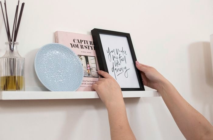 Wall-mounted shelf with a book, plate, vase and photo frame