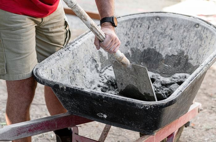 Person mixing mortar in a wheelbarrow.