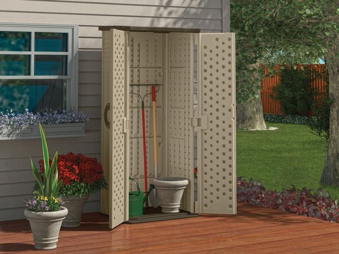 Backyard deck with a storage unit containing garden tools against the house wall