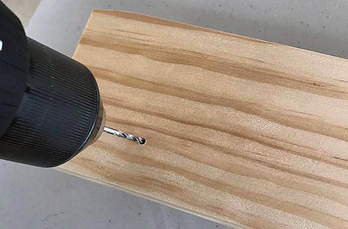 Holes being drilled into a coat rack to add dowel coat pegs