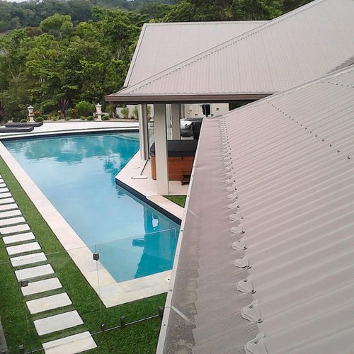 Close up of a roof image with an installed gutter mesh and an outdoor swimming pool.