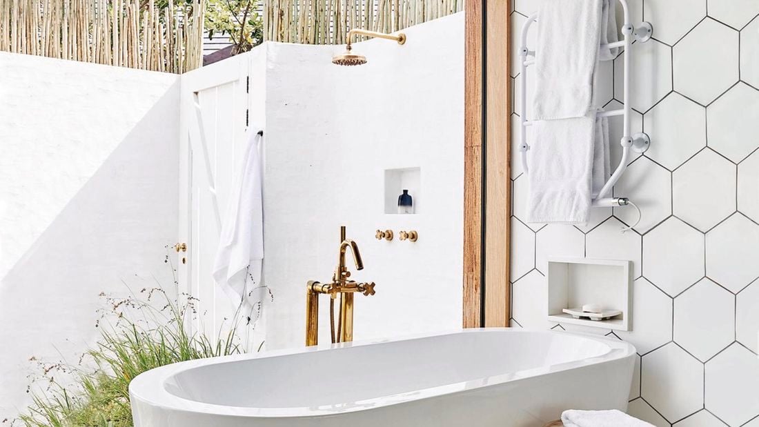 White modern bath with a brass outdoor shower.