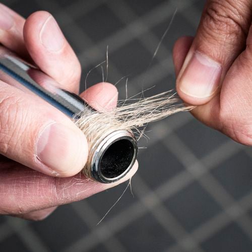A person applying plumbers hemp on a threaded bar.