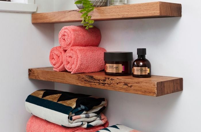 Timber wall shelves with towels and bathroom products sitting on them.