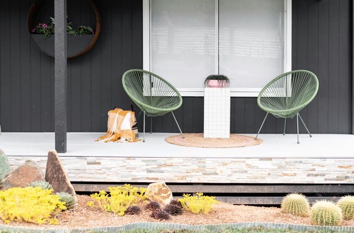 A finished tiled table, positioned between two outdoor lounge chairs on a verandah.
