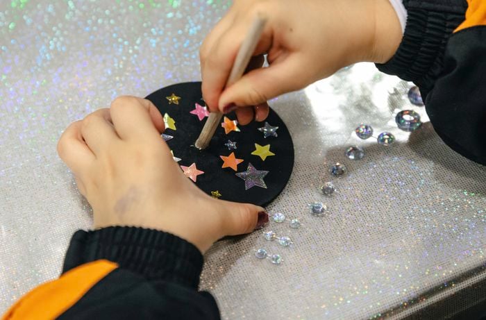 A length of wooden dowel being applied to a circular coaster decorated with stars