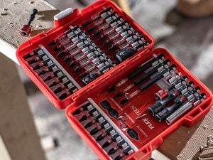 An open case containing a full set of power drill bits sitting on a length of wood