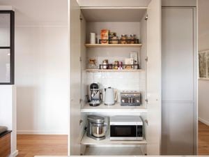 An open cupboard showing various appliances neatly arranged on shelves inside.