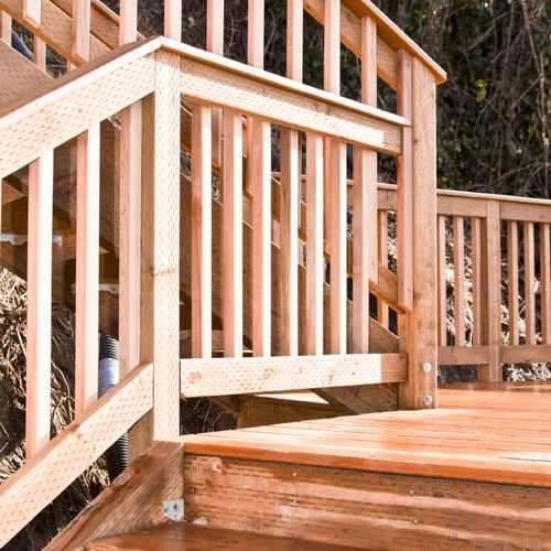 Timber deck with railing on a sloped outdoor area.