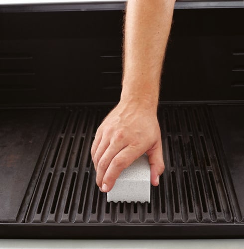 Person cleaning barbecue with sponge