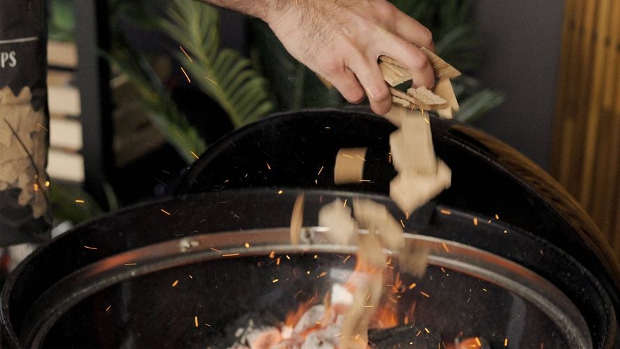 Smoking Chips being sprinkled out of a hand over lit coals