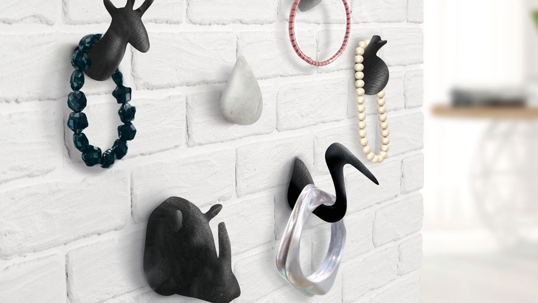 Various animal-shaped wall hooks with jewellery hanging off them.