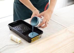 Pouring paint out of a paint pot into a paint tray