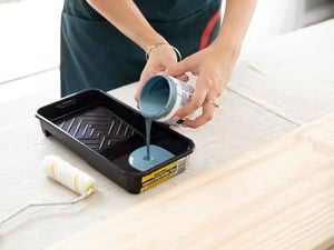 Pouring paint out of a paint pot into a paint tray