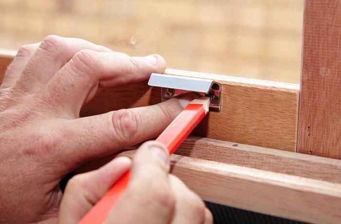 Person marking a screw hole for a window lifter on a window frame