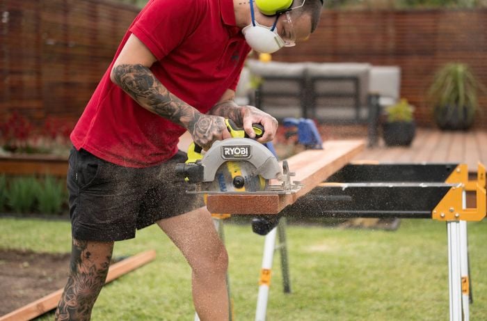 A Bunnings Team Member is using a Ryobi circular saw to cut the timber sleepers to the required lengths.