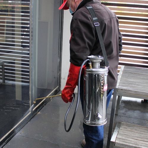 Man with steel silvan sprayer is spraying the bottom of a building window