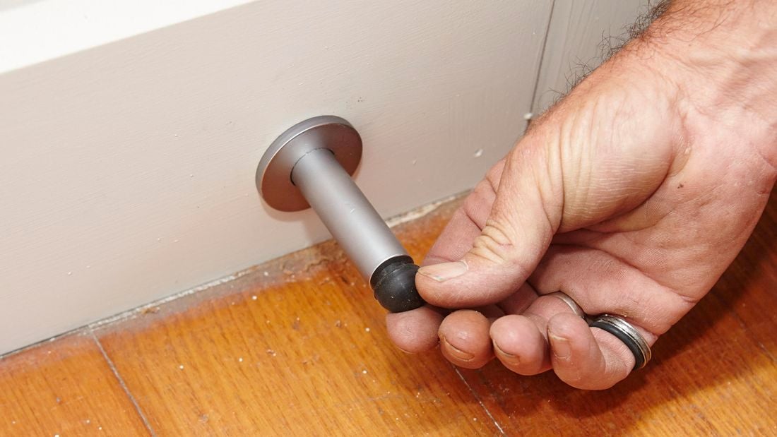 A person attaching the rubber end to a door stop