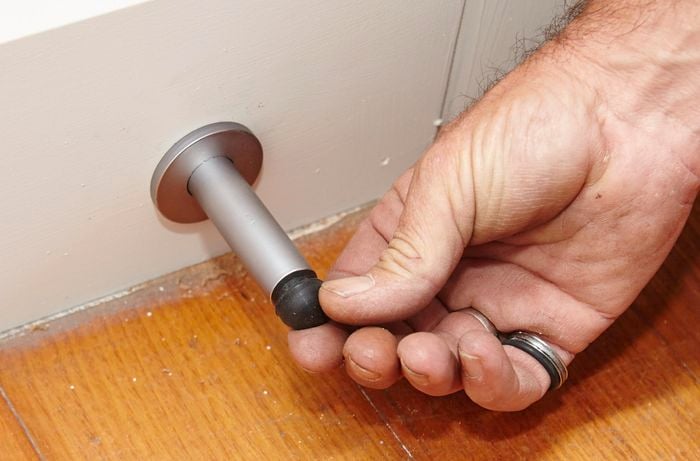 A person attaching the rubber end to a door stop