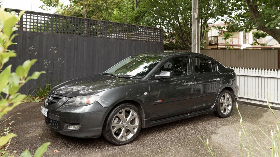 A steel grey Mazda SP23 is parked in the shade of a tree.