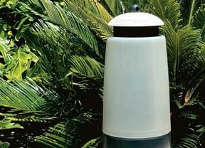An EnviroSafe outdoor white fly trap against a backdrop of palms and other greenery.