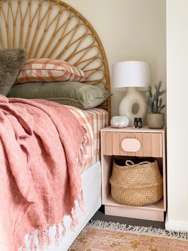 Pink wooden bedside table next to a bed painted with Coloursmith