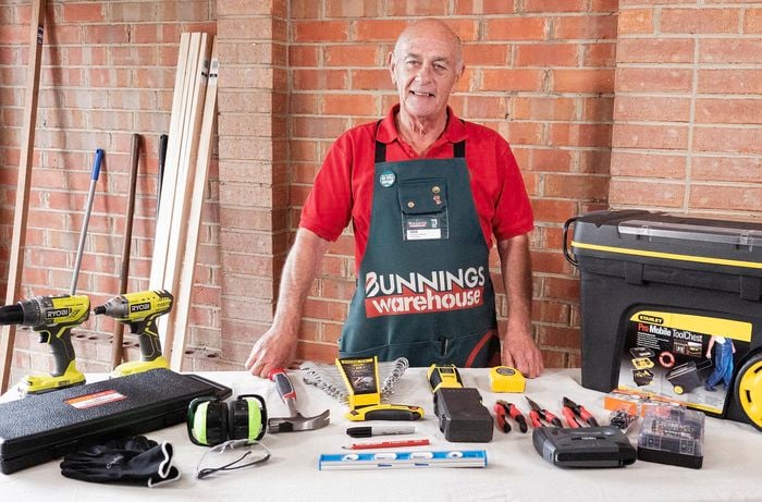 Person standing behind desk with lots of tools on it.