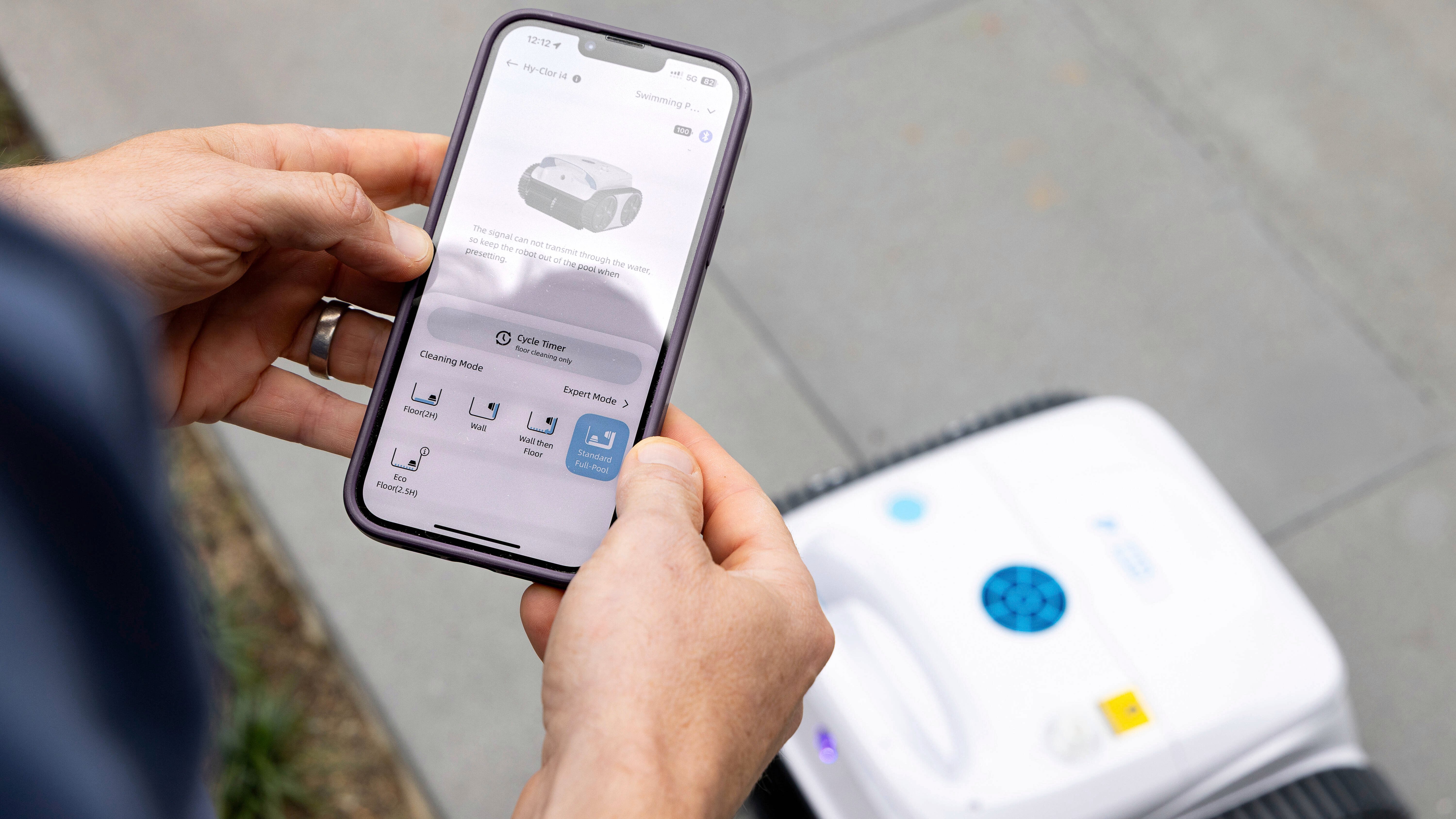Person using a smartphone app to control a robotic pool cleaner.