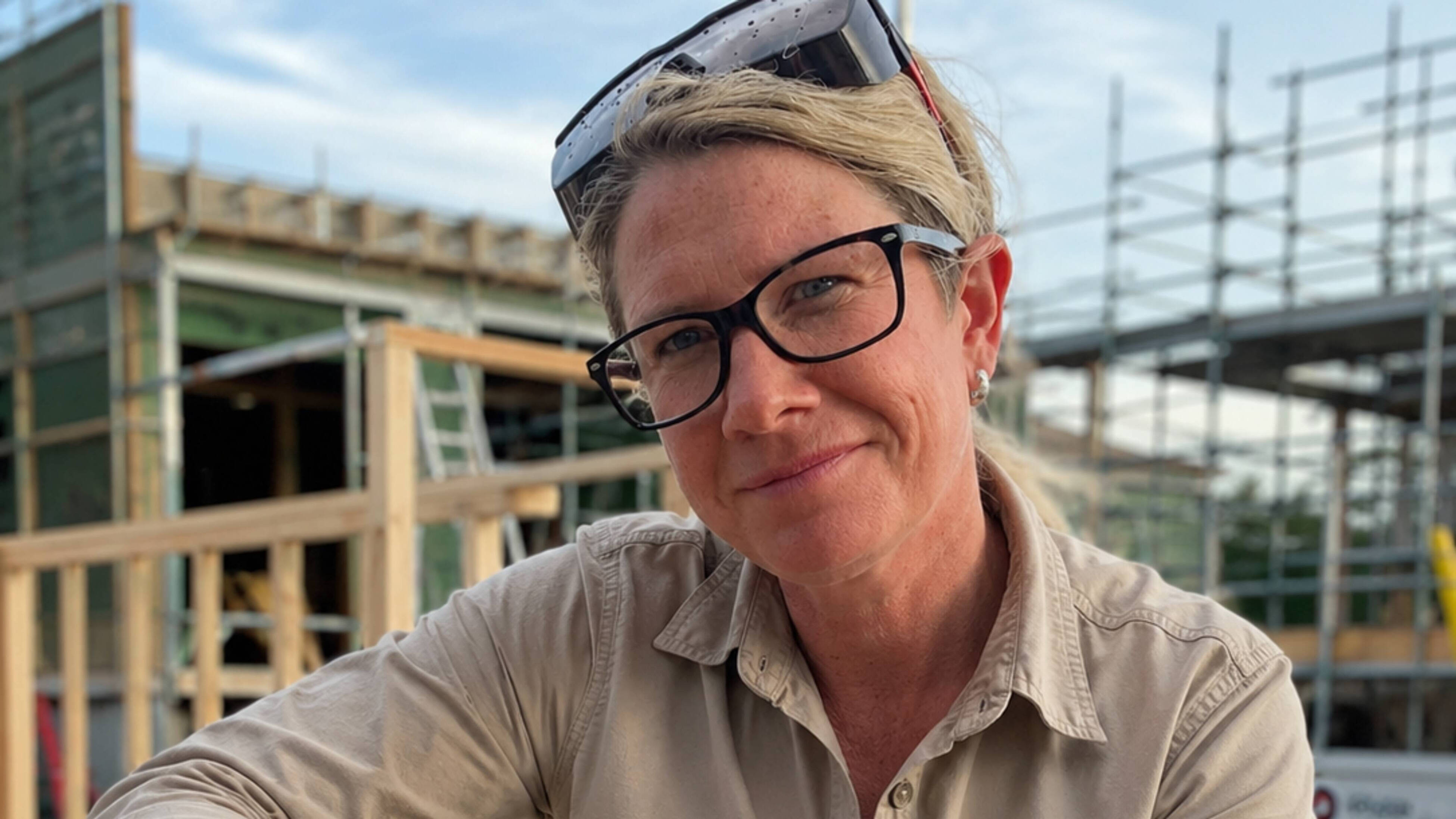 A female carpenter looks at the camera with a worksite in the background in Hobart, Tasmania.