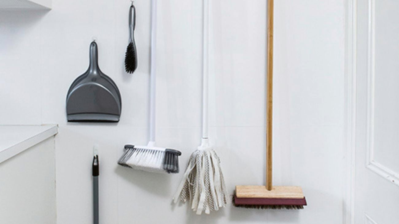 Dustpan and brooms hanging from a wall using grippers.