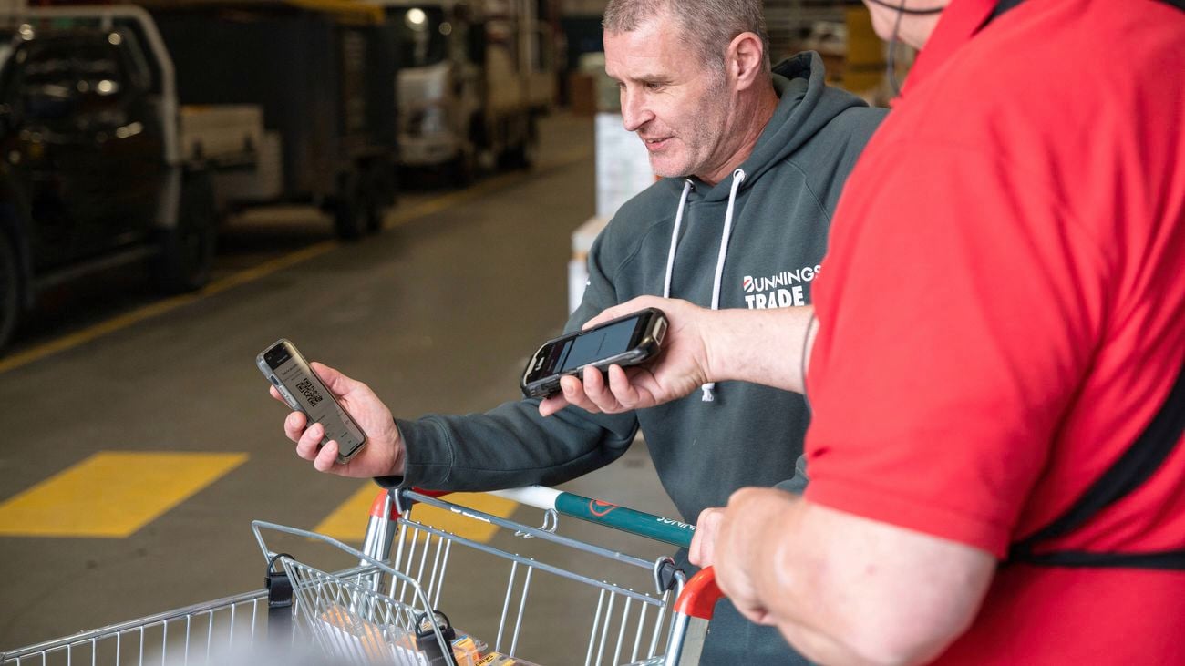A Bunnings Trade staff member scans the QR code on the phone of a customer who is using the Bunnings Trade PowerPass app
