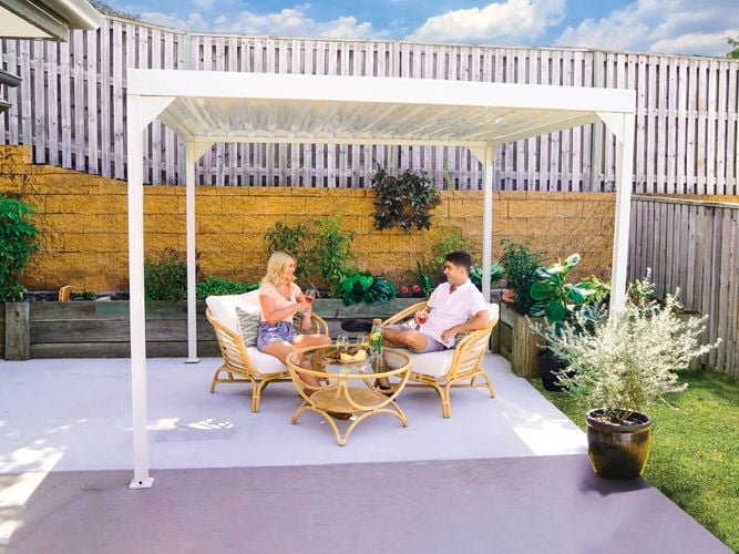 A man and woman drinking around a small outdoor setting under a gazebo.