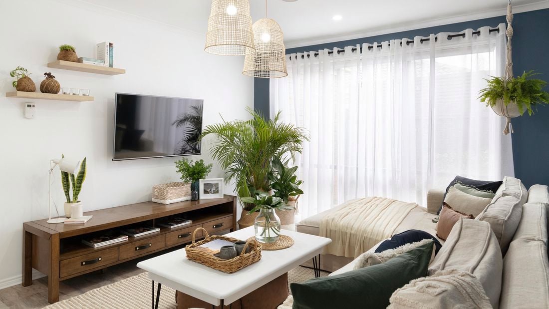Blue lounge room with white couch, white coffee table and TV unit.