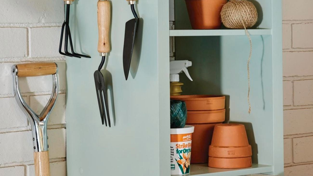 Storage cube filled with pots and gardening tools.
