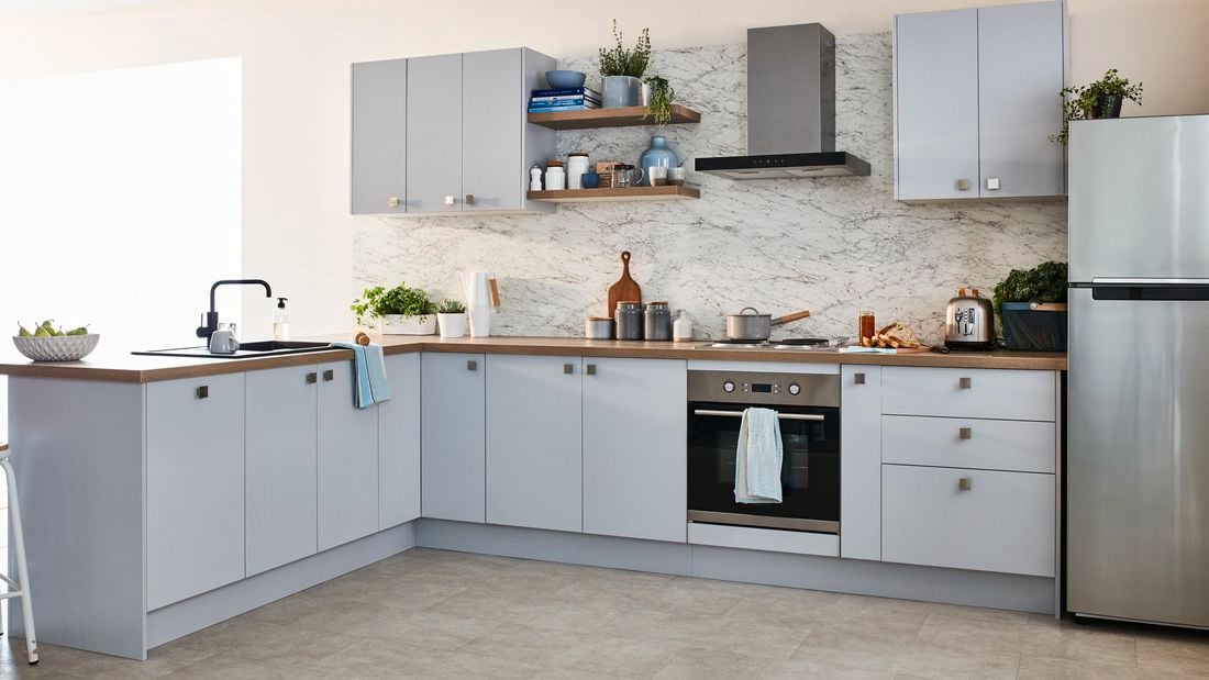 Kitchen with blue cabinetry, marble splashback, and silver appliances.