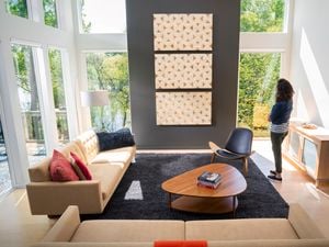 Person looking at wall prints hung on wall in a living room.