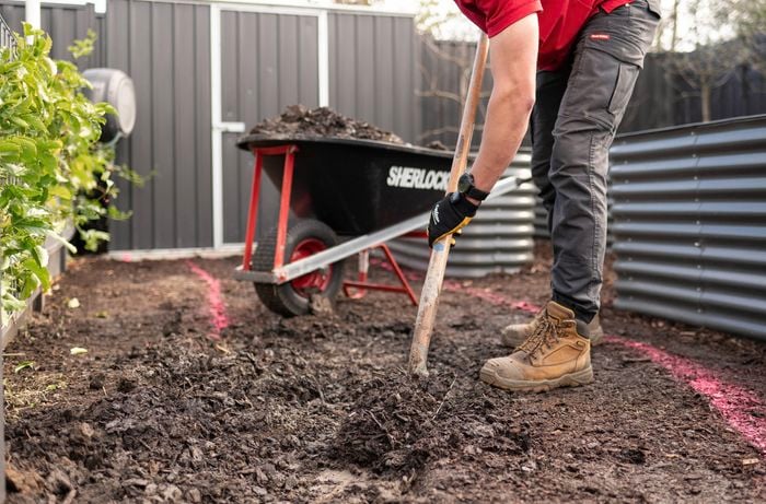 A person is digging the soil with a shovel.