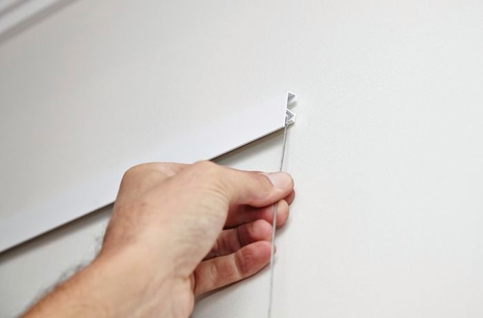 A track being fitted on wall mounted brackets, showing the track edge facing downwards
