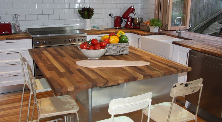 Retro style kitchen with chairs around an island bench with composite wooden benchtop