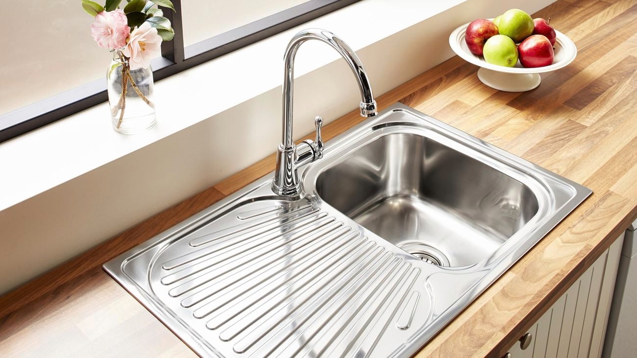 Silver/chrome overmount kitchen sink on top of a wooden benchtop.