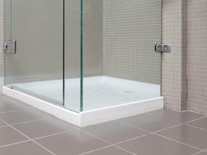 A shower with a glass door in a bathroom with tiles on the walls.