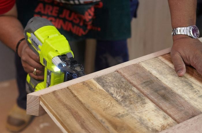 Person using nail gun to nail table sides to tabletop